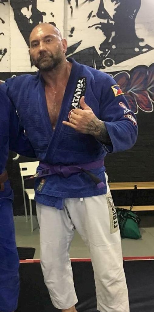 WWE superstar Dave Bautista wearing his Jiu Jitsu purple belt on the mats